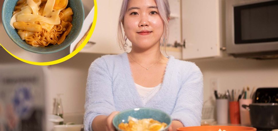 Photo of Sophie Lee (Questrom’22), wearing a light blue sweater and smiling, as she holds a teal bowl of Tteokbokki in front of her. Overlaid on the photo at the top left is a top-down view of the bowl of Tteokbokki, which has noodles, a reddish sauce and a soft-boiled egg.