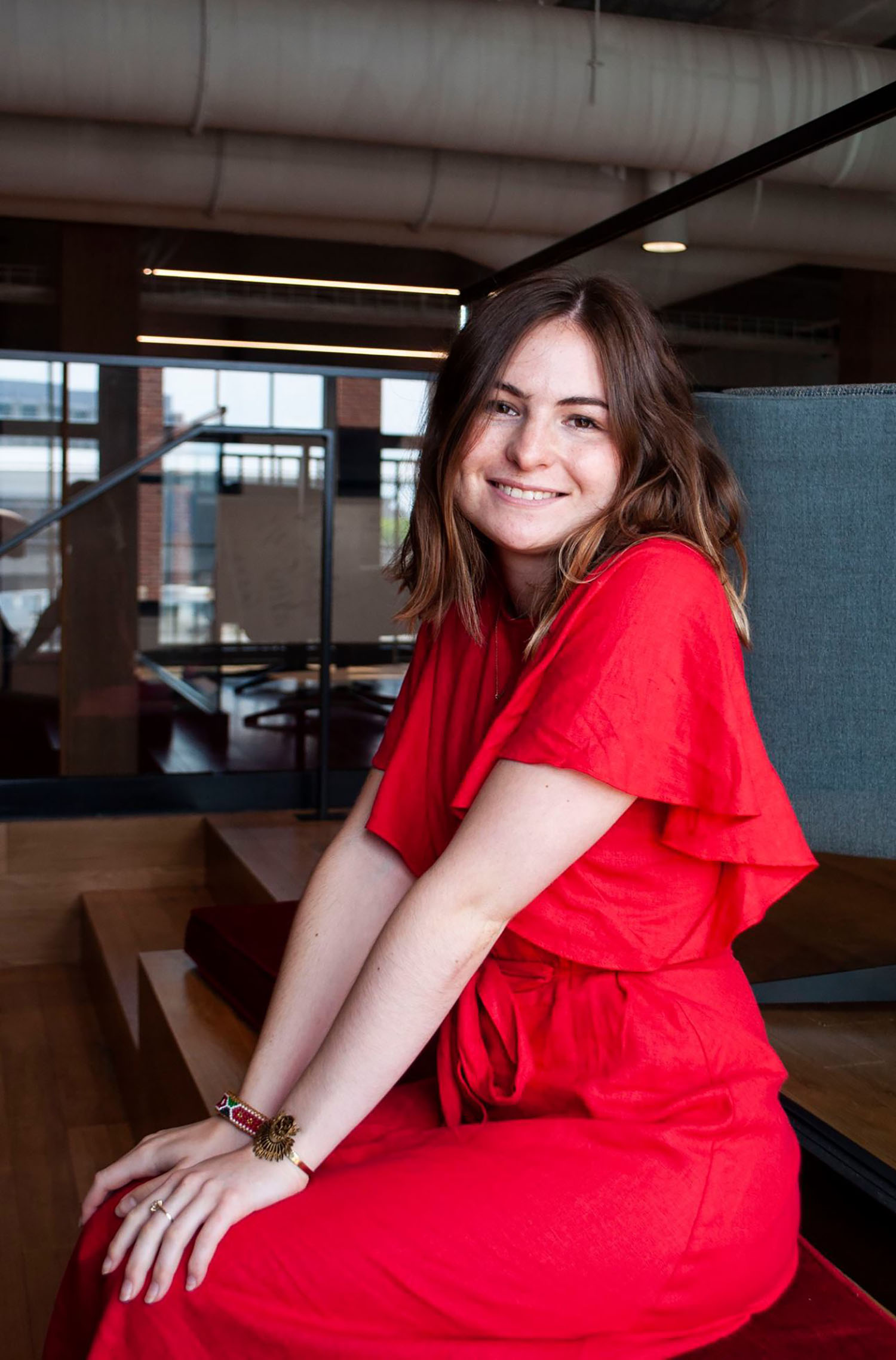 Photo of Fiona Whittington wearing a red dress and sitting her hands in her lap.