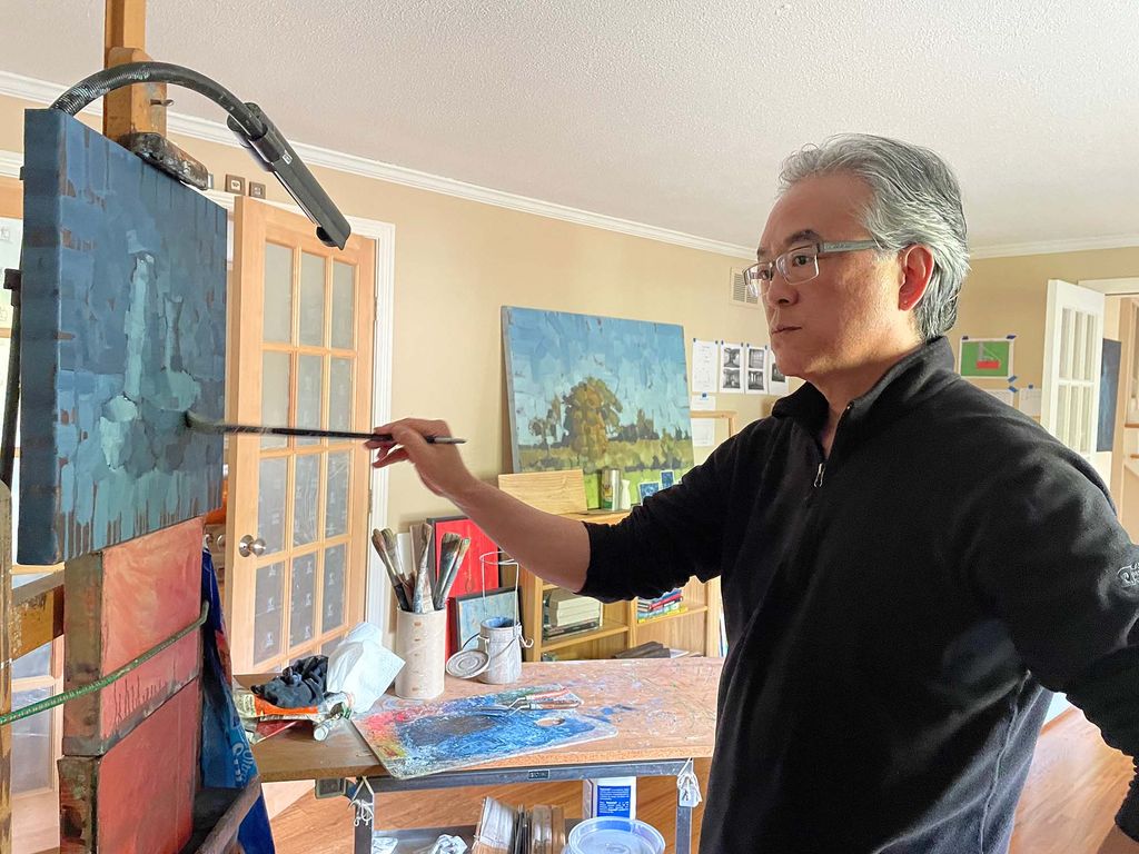 photo of the artist Aaron Caycedo-Kimura working on a painting in his studio.