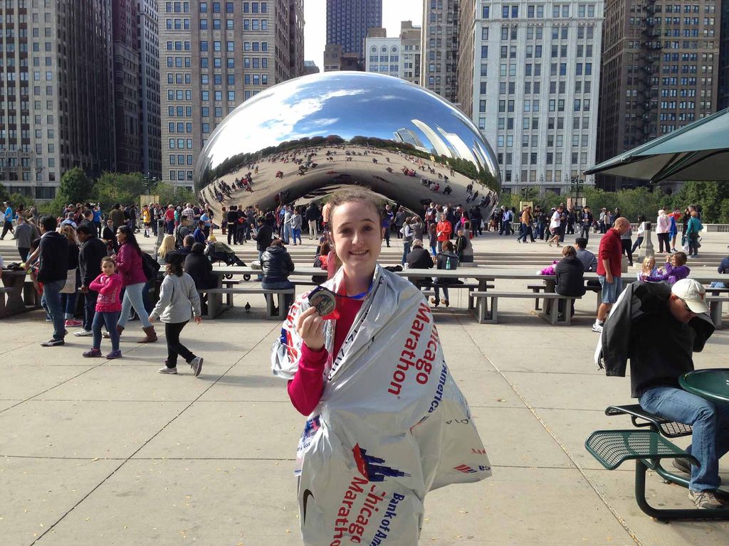 Madison Jolly poses in front of the Cloud Gate sculpture holding her medal after finishing the Chicago Marathon.