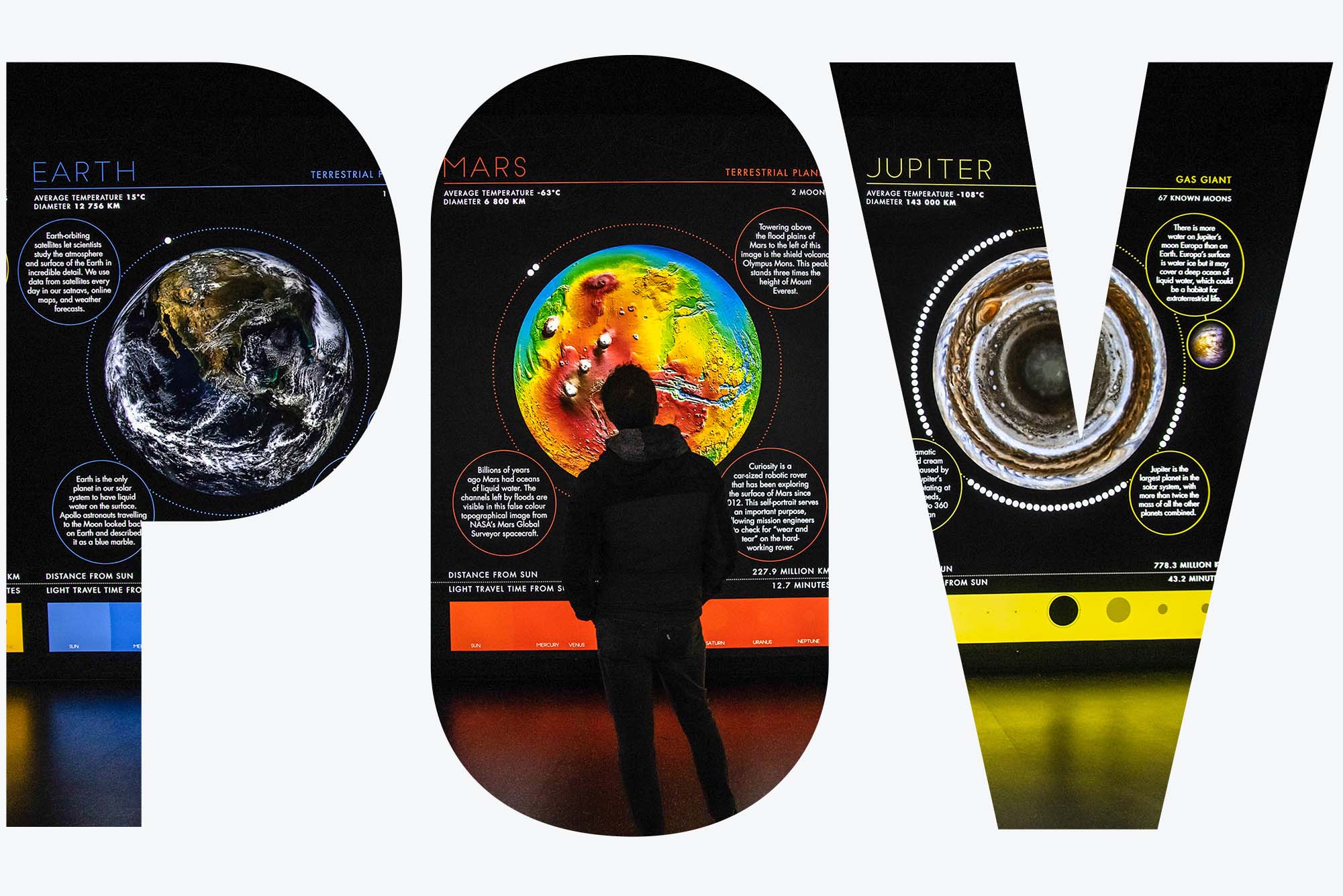 A visitor views a Green Zone exhibit during the COP26 climate talks in Glasgow, U.K., on Monday, Nov. 1, 2021. He stands in a dark room facing a bright, colorful display showing the differences in climate on Earth, Mars, and Jupiter. Image overlaid with letters "POV"