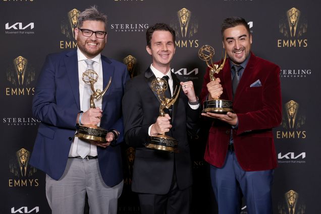 photo of Franco Zuccar (from left), Steve Vitolo, and Felipe A. Mendez of Scriptation with their statuettes at the 73rd Engineering Emmy Awards. They stand in front of a black backdrop with the Emmy logo repeated on it.