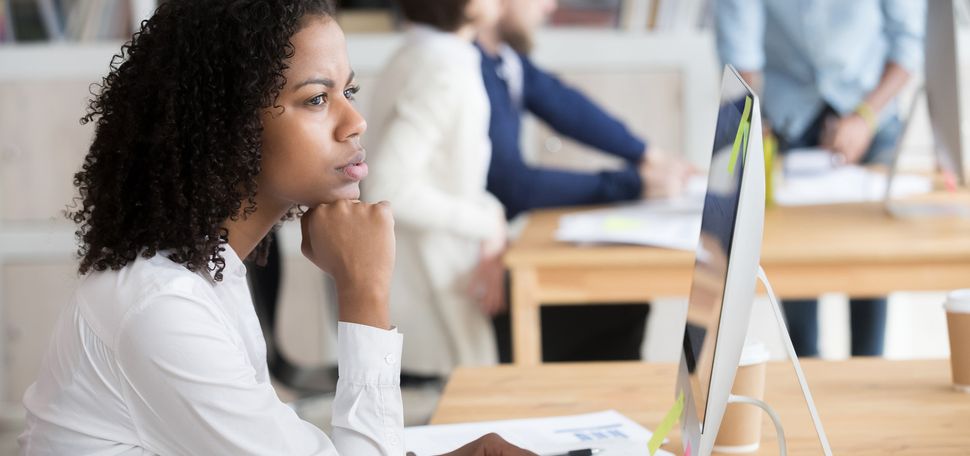 a stock photo of a serious black female employee thinking sitting in front of computer