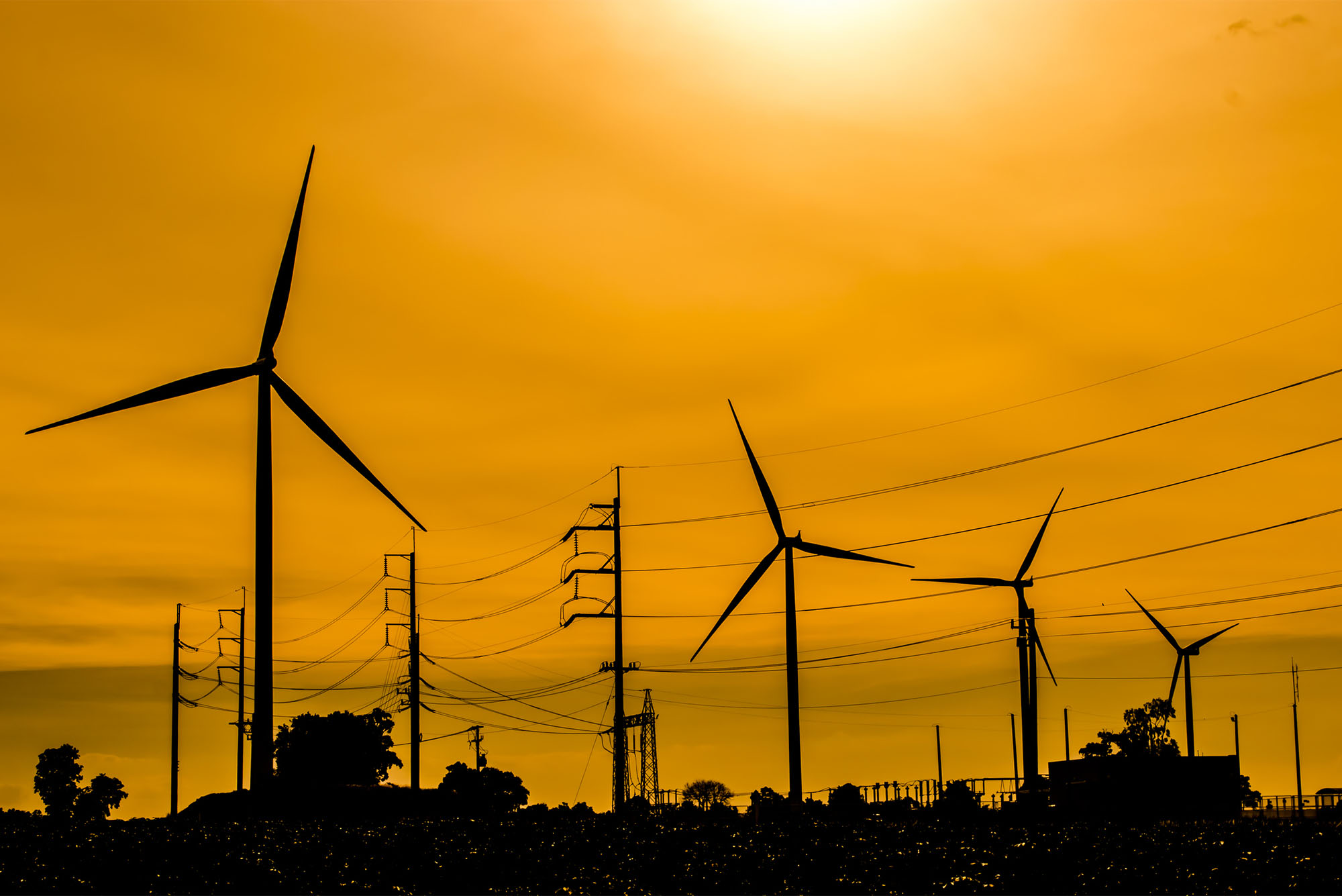 The silhouette of 3 windmills a against a sunset sky. Photo by iStock/Naruden