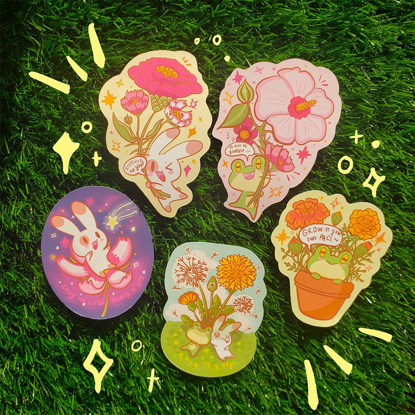 Overhead photo a various stickers on lush green grass. Stickers feature cute cartoons of rabbits