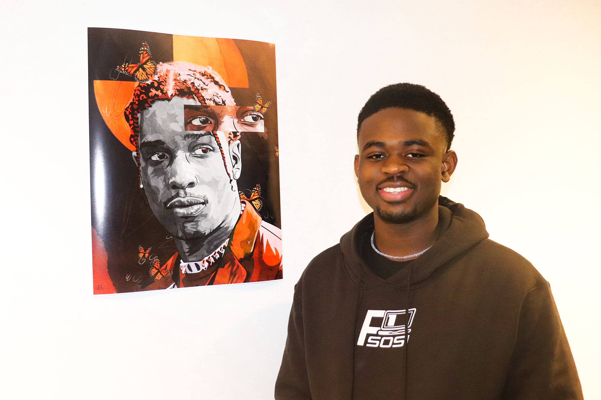 photo of Perry Sosi posing next to a portrait he drew posted up in a gallery