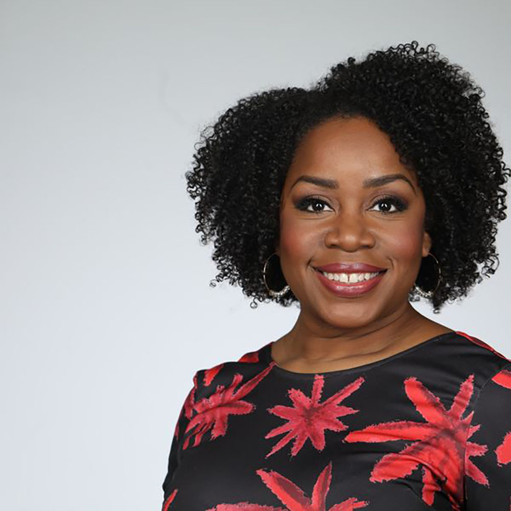 Photo: A portrait of Atkins Stohr, a Black woman wearing a black top with red florals
