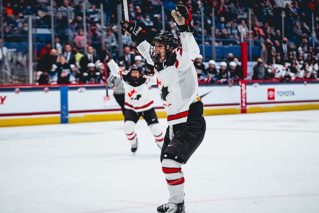 Photo ofMarie-Philip Poulin (CAS’15) skating as part of Team Canada at the Winter Olympics in 2010 and 2014. She raises her hands and stick above her head in celebration.