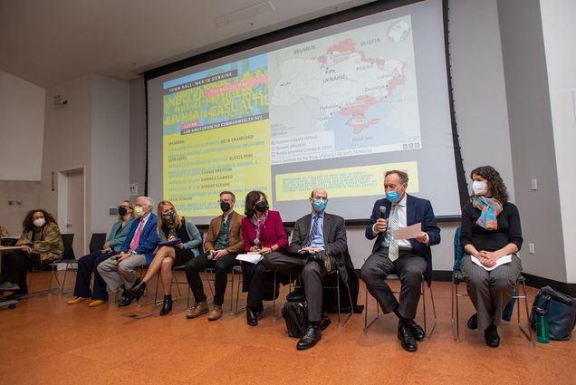Photo of the panelists who participated in the Ukraine Town Hall hosted at the LAW Auditorium March 17. The panelists sit in black metal chairs, in the following order, from left: Neta Crawford, CAS professor of political science, Kaija Schilde, Pardee School of Global Studies Associate Professor of International Relations and acting director, BU Center for the Study of Europe, Joe Wippl, US diplomacy, Carrie Preston, Chandan Nandlal Kilachand Professor and Kilachand Honors College director and a CAS professor of English and of women’s, gender, and sexuality studies, Nicholas Micinski, Assistant Professor of Political Science and International Affairs at the University of Maine and a former visiting visiting researcher at BUs Center for the Study of Europe, Daniela Caruso, School of Law professor of Law, Robert Sloane, LAW professor of law, Igor Lukes, CAS professor of History, and Alexis Peri, CAS associate professor of History. Behind them, a projector shows a map of Ukraine and the areas Russian is attacking.