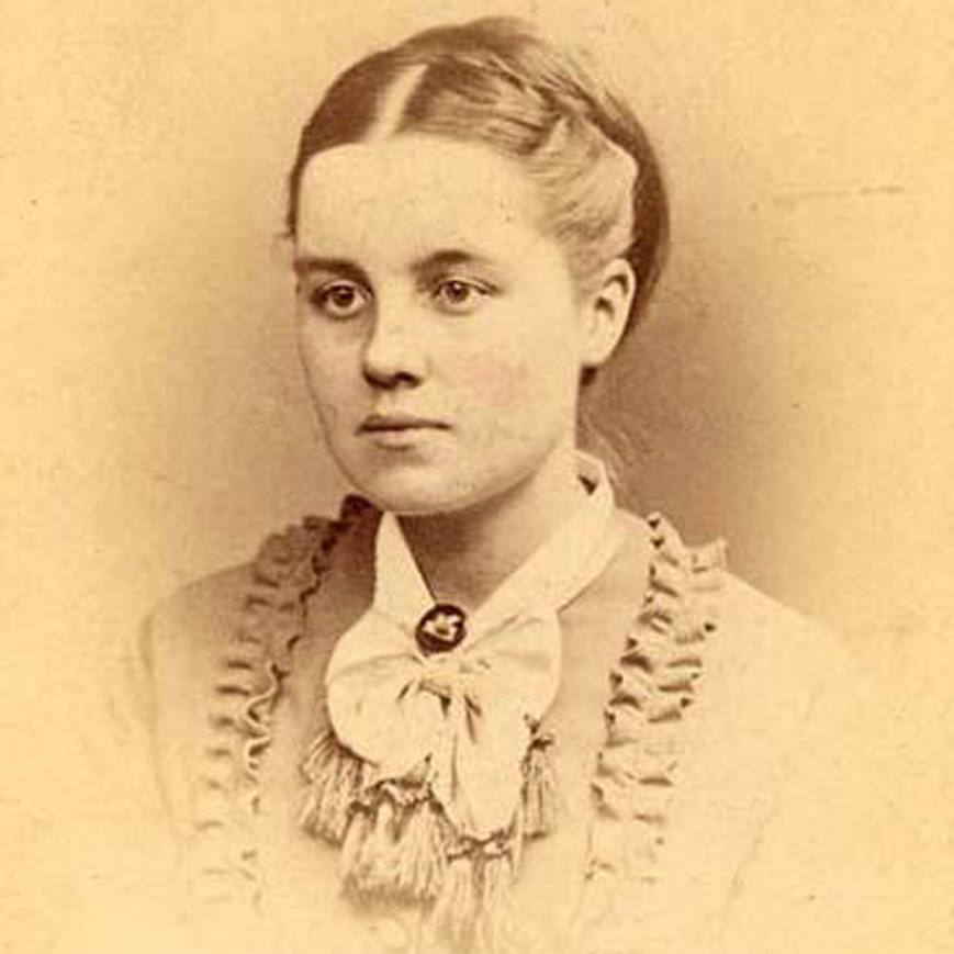 Photo of Helen Magill taken in 1873. Faded, brown photo of a white woman with hair tied back in intricate bun looking to the left with a neutral expression