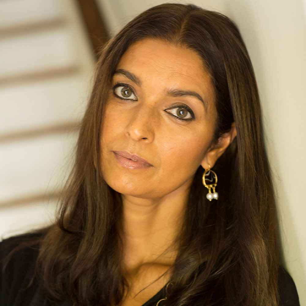 Headshot of Jhumpa Lahiri in a black blouse, gold necklace and earrings.