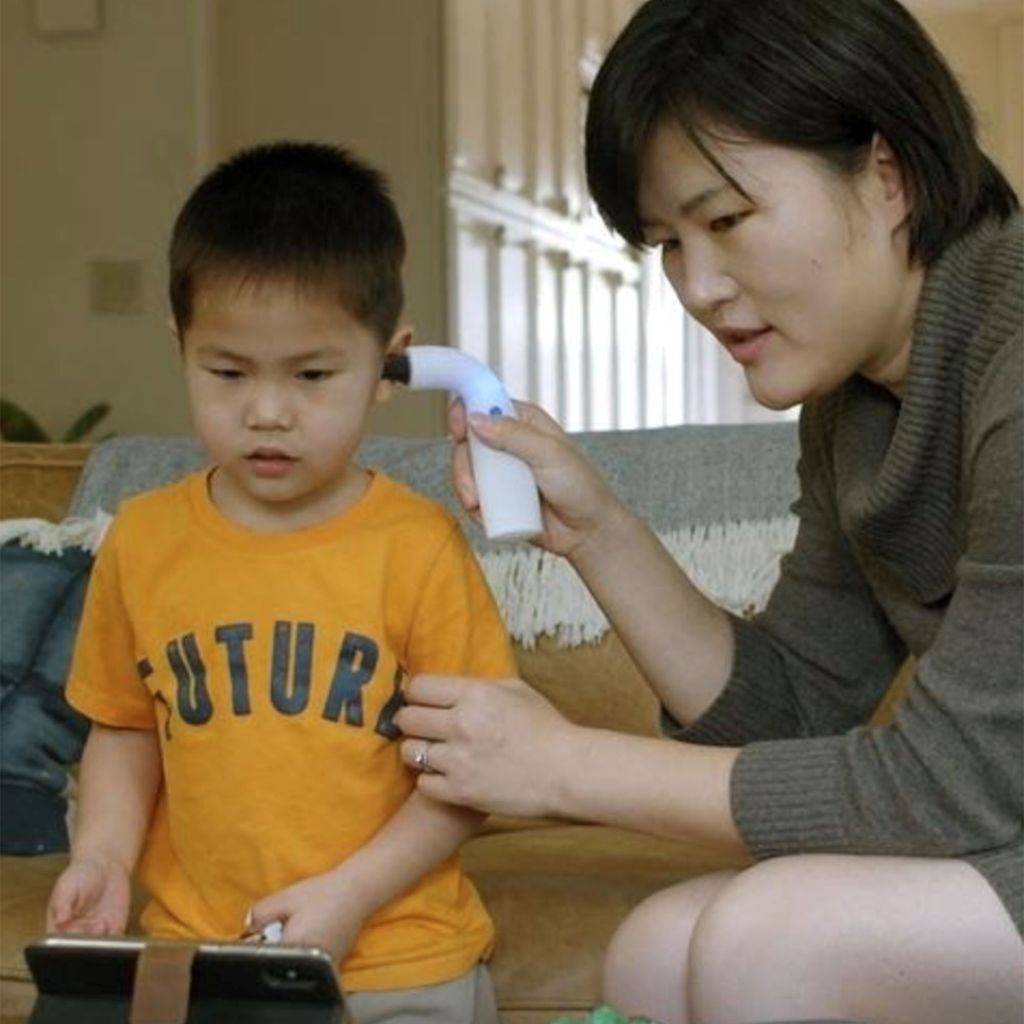 Jane Zhang uses the ear infection detection device she designed on her son's ear