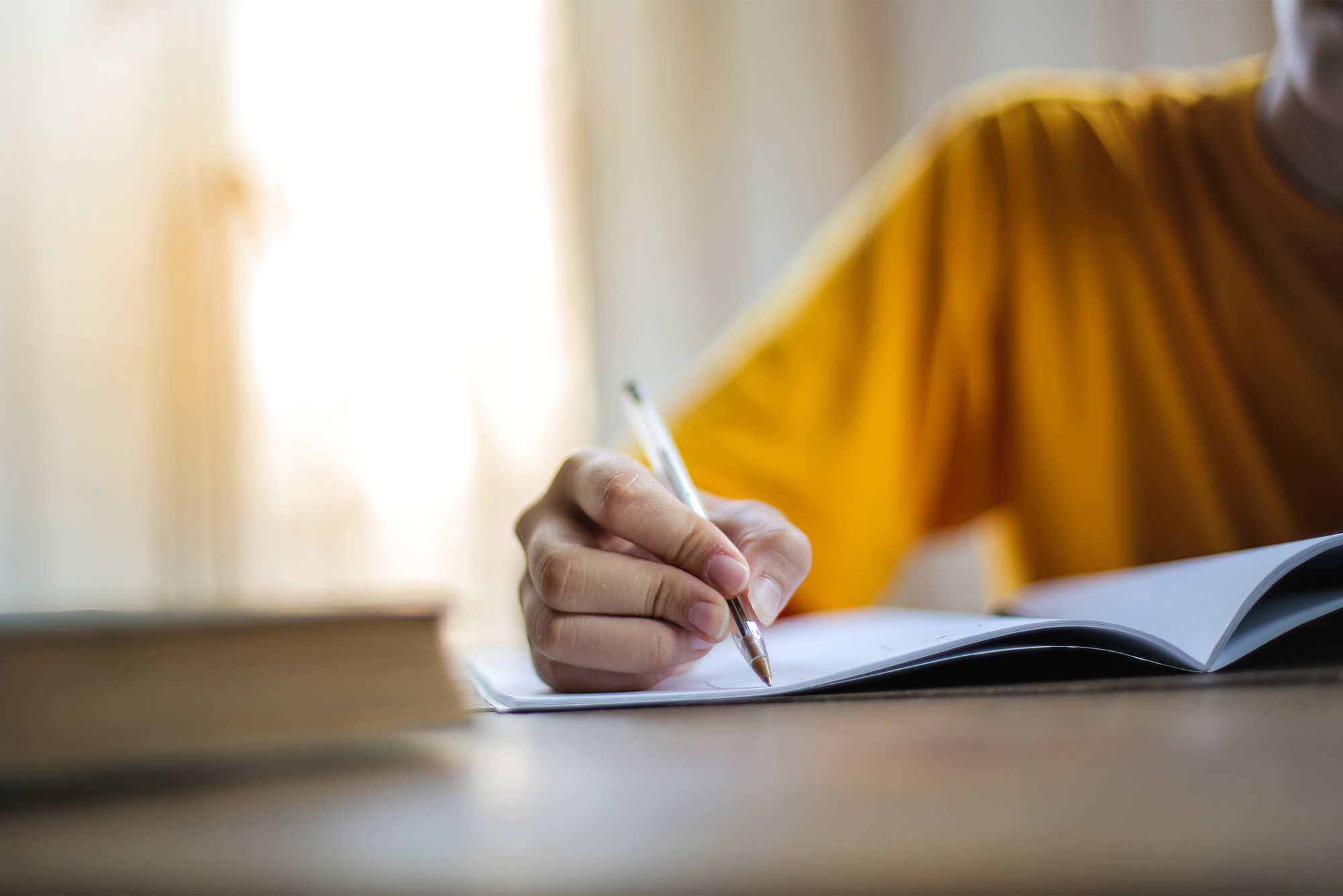 a person's hand writes on a pad of paper with a pen