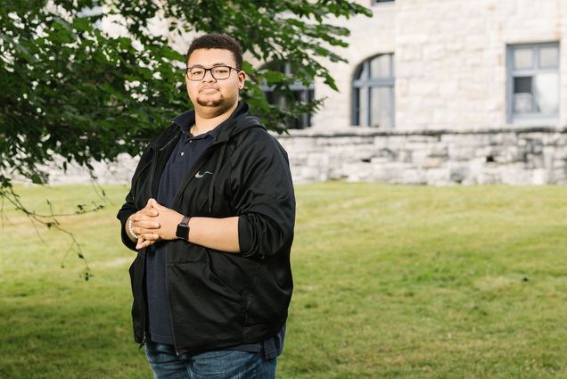 BUTI student Dorian Parker stands outdoors in a black shirt with glasses on