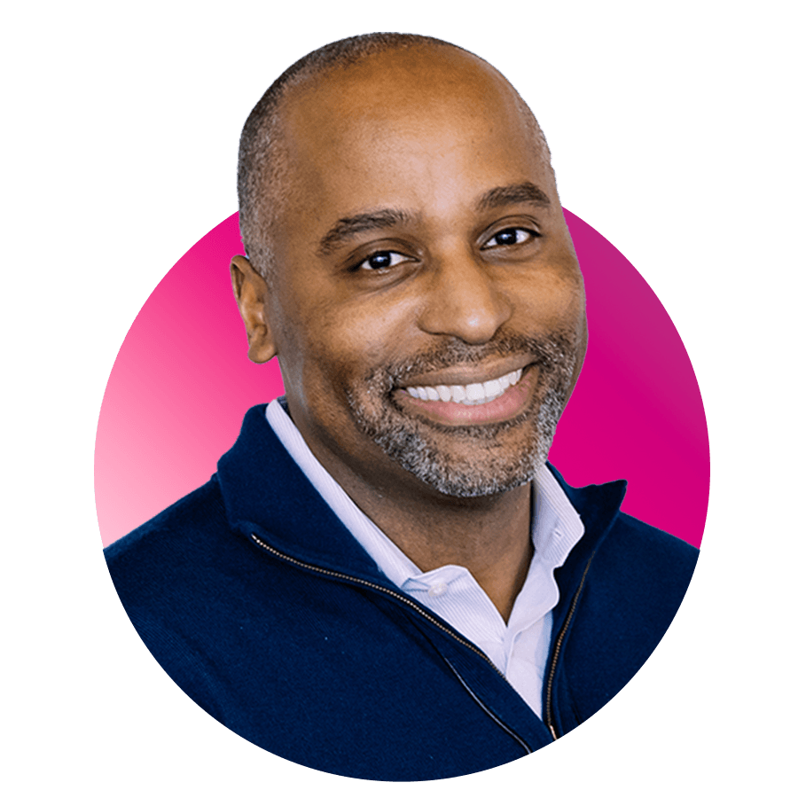 Headshot of CFA Dean Harvey Young, a middle-aged Black man, who smiles and wears a blue quarter zip. A pink circle is photoshopped behind his head for emphasis.