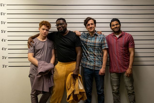 A group of for students pose for a photo in front of a police lineup board