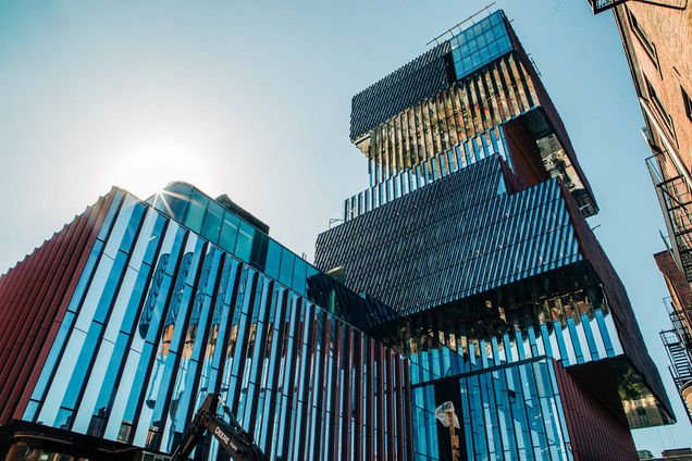 Photo: View of the Center for Computing and data Sciences from Commonwealth Ave. From this viewpoint, the sides of the building alternate a copper color and a reflective mirror side. It is shown from below to highlight the "bookcase" design and the reflective nature of the sides.