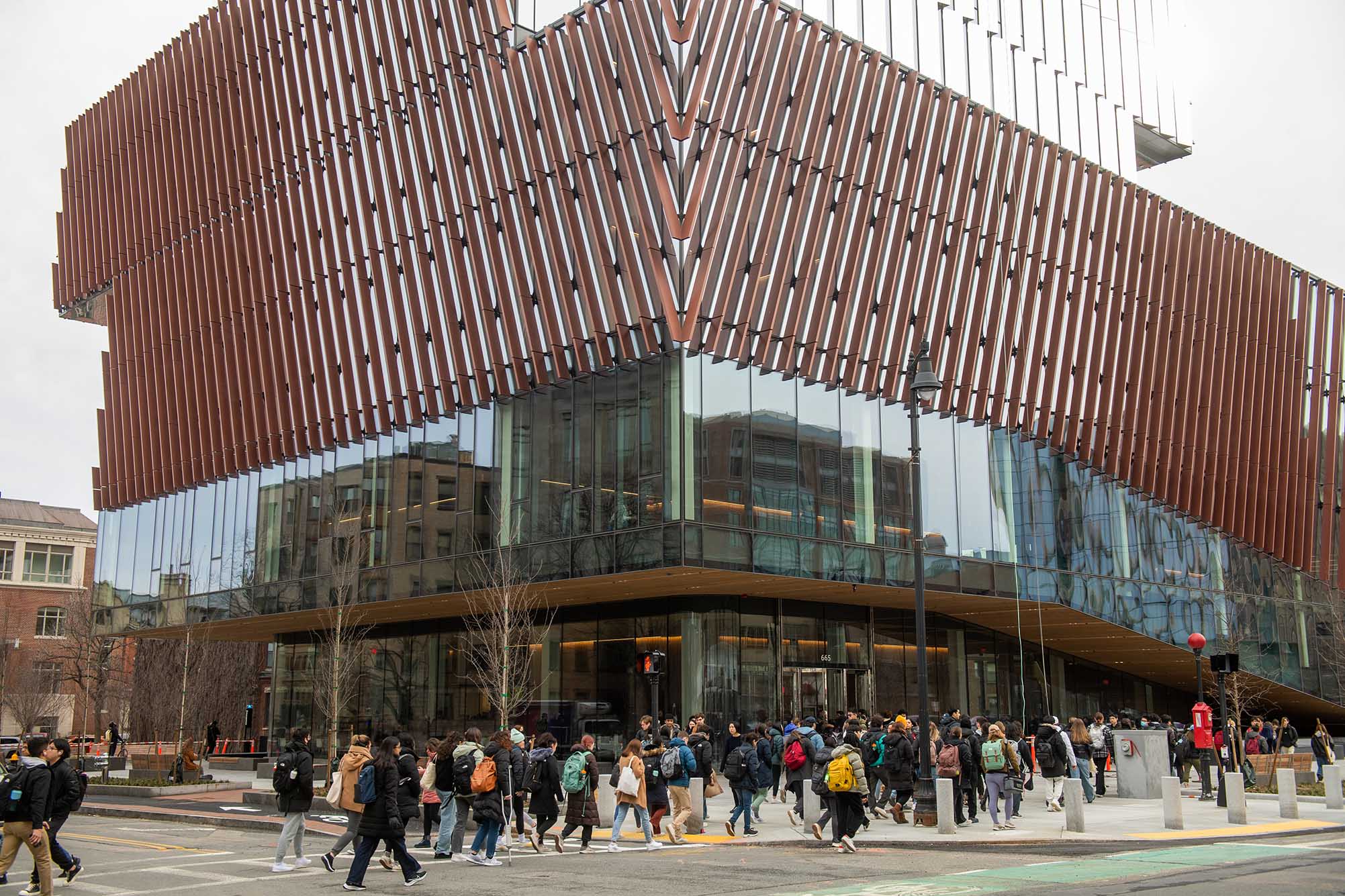 Photo: First day of classes foot traffic passing by the Center for Computing & Data Sciences January 19. A modular brown and glass building shows students and pedestrians walking around.