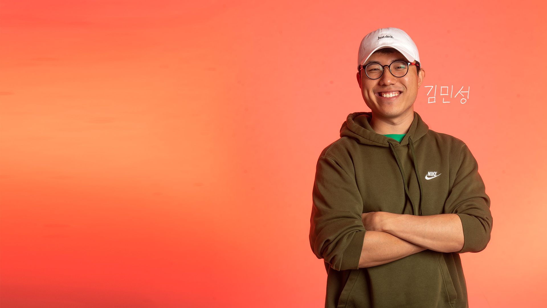 Photo: An Asian man with a white cap and a green sweatshirt crosses his arms as he looks into the camera.