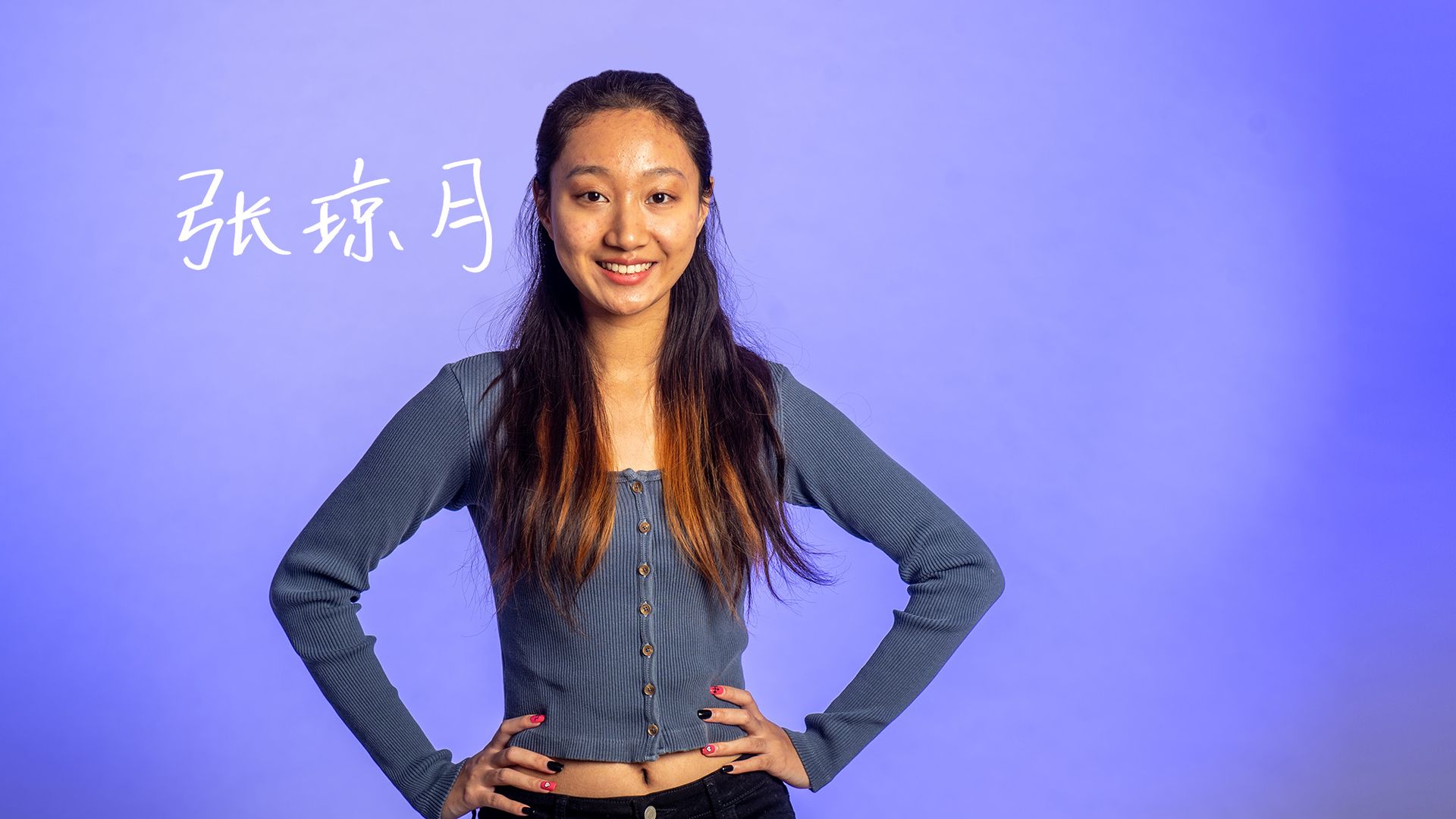 Photo: An Asian woman standing with her hands on her hips, smiling at the screen.