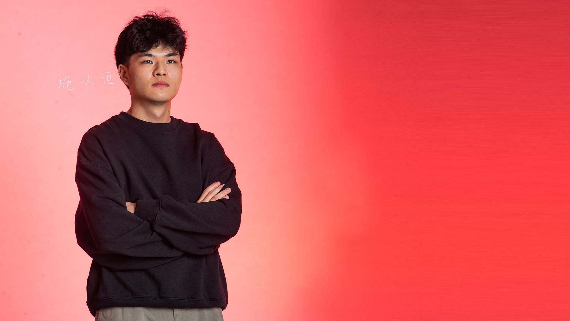 Photo: A Asian man with a long black sleeve shirt crosses his arms as he looks past the camera.