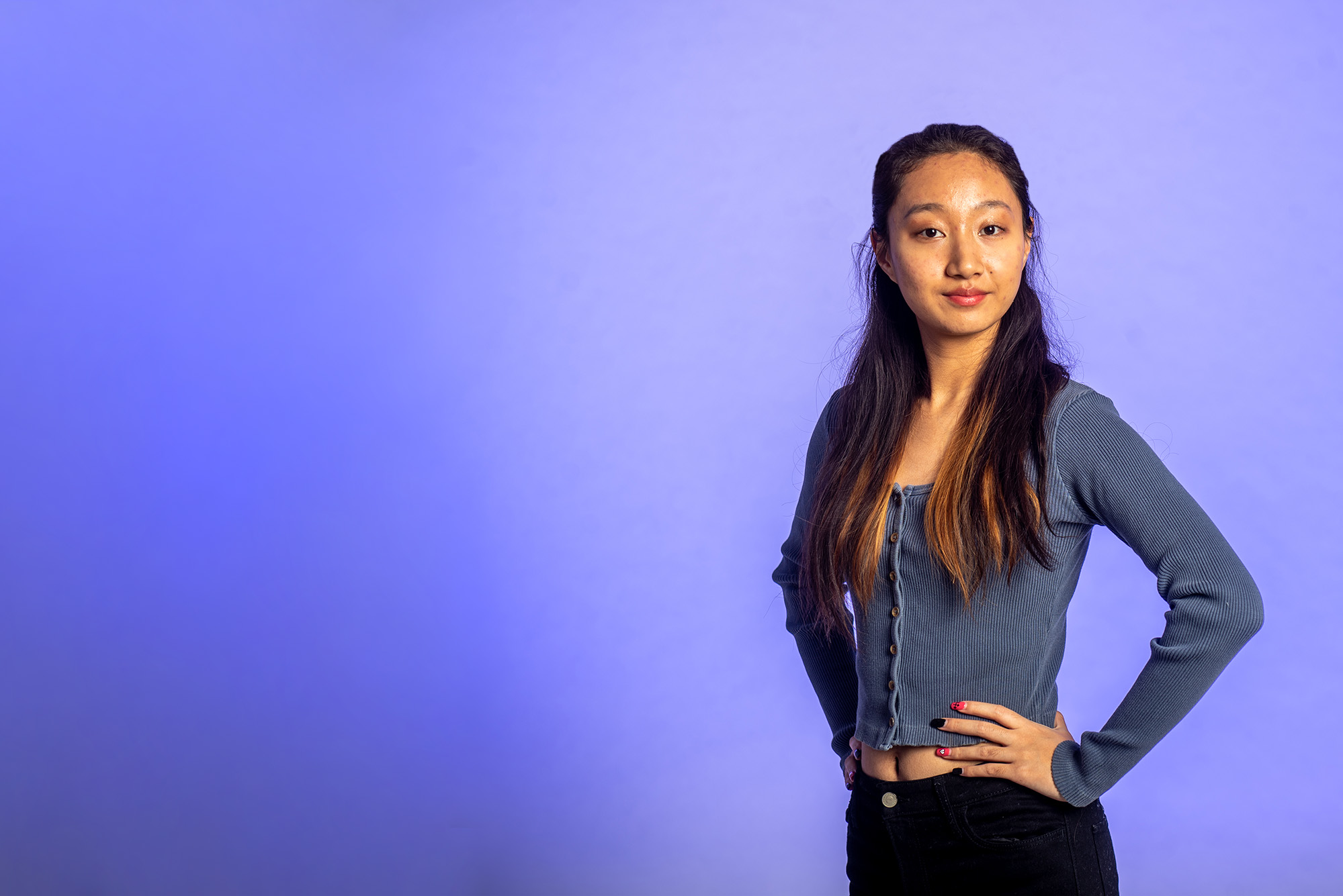 Photo: An Asian woman standing with her hands on her hips, smiling at the screen.