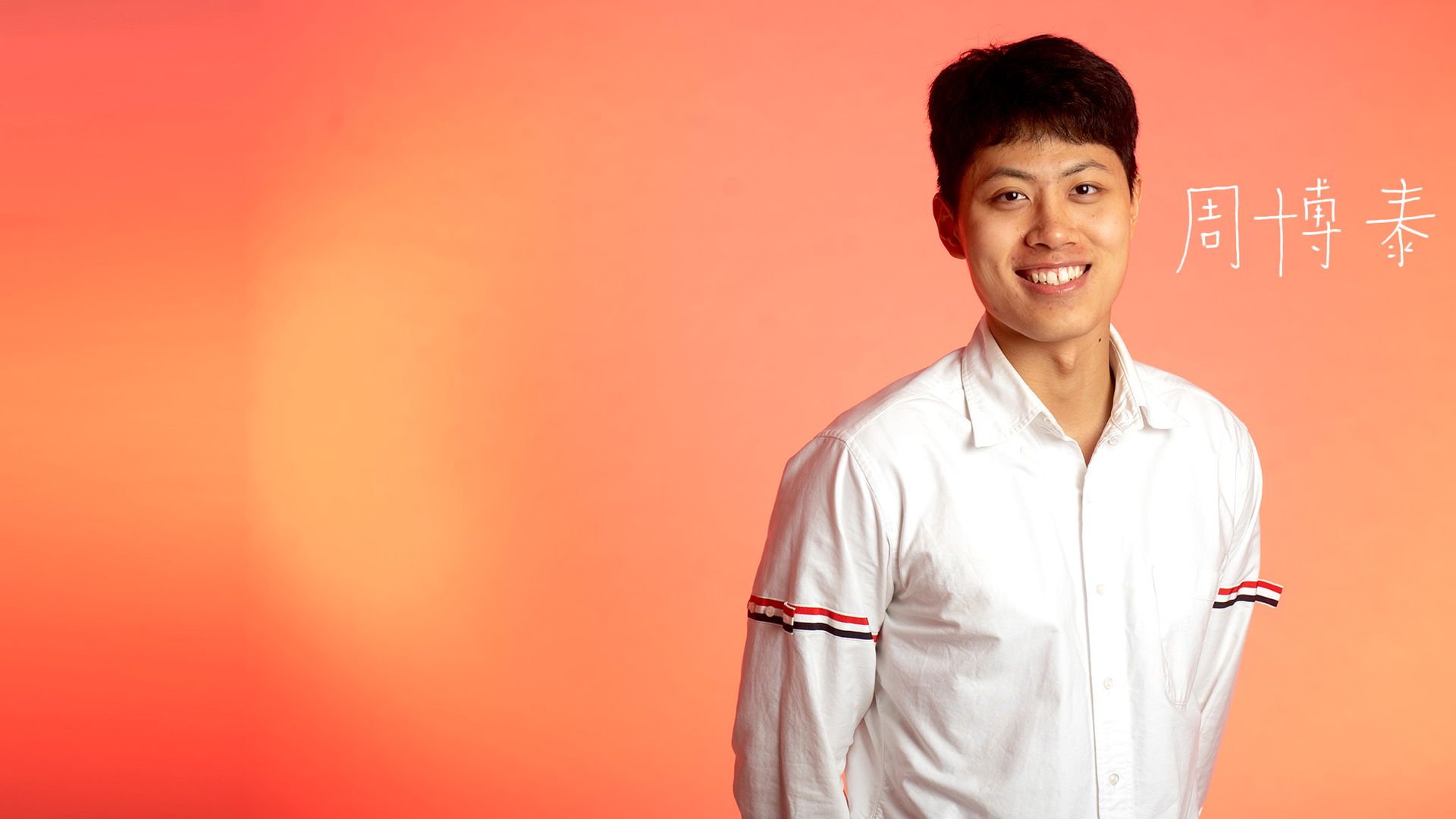 Photo: An Asian man with a white button up shirt stands and smiles at the camera.