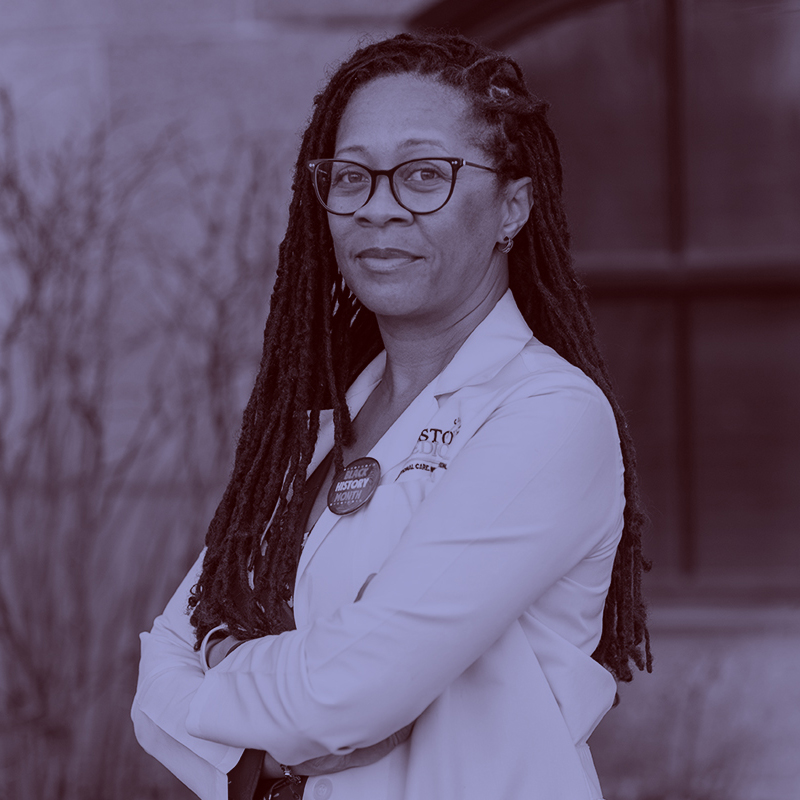 Photo: Dr. Vonzella Bryant, a black woman with long dreadlocs wearing a red floral dress and lab coat, poses with arms crossed. A light purple filter overlay is placed over the photo.