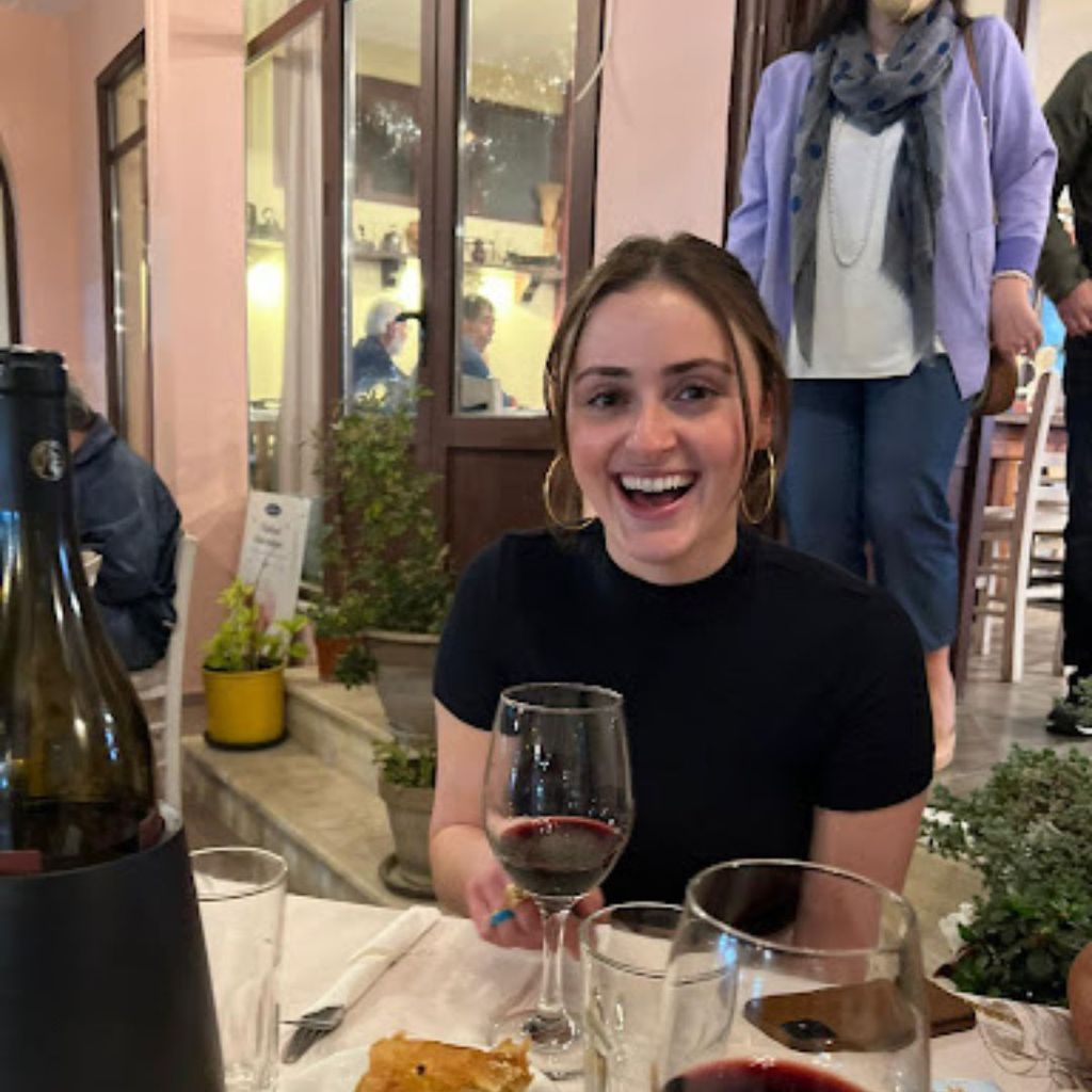 Student, Samantha Ruh, is pictured sitting at an outdoor restaurant with a big smile on her face.
Picture credit: Samantha Ruh (SHA'23)