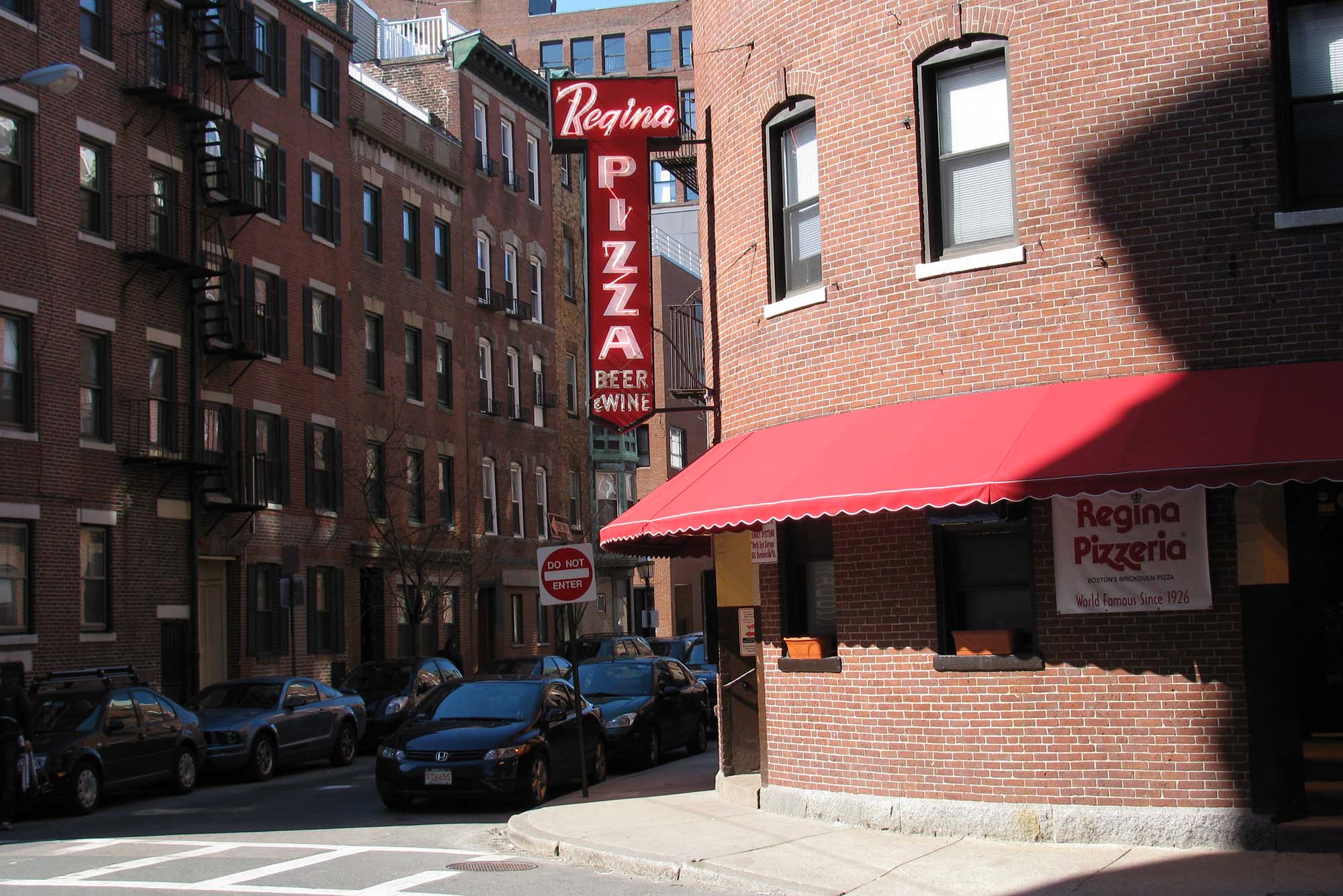 Photo: The building facade of Regina Pizzeria in Boston's North End, featuring a neon sign with "Regina Pizza" outside