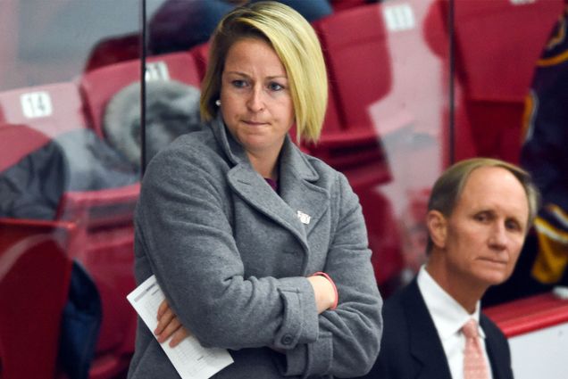 Photo: Tara Watchorn (Sargent’12), a white woman with short blonde hair standing with arms crossed behind the BU Women's Hockey bench in 2019-20, when she served as assistant women’s ice hockey coach, with longtime head coach Brian Durocher (Wheelock’78) an older white man wearing a suit and tie, standing to her right.