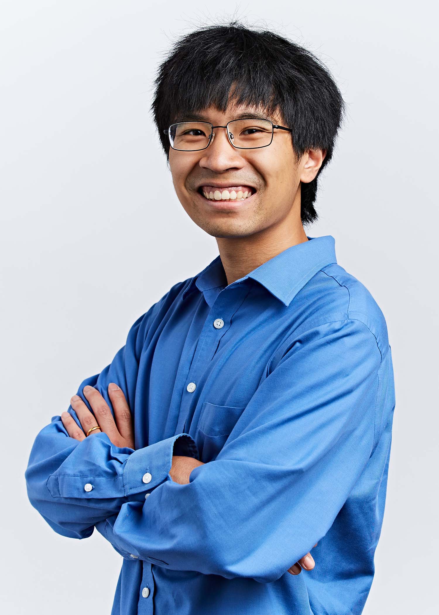 Studio portrait of Mark Bun in San Francisco, CA on September 28, 2018. He is a young, Asian man with short black hair and glasses. He smiles, his arms crossed, and wears a blue collared shirt.