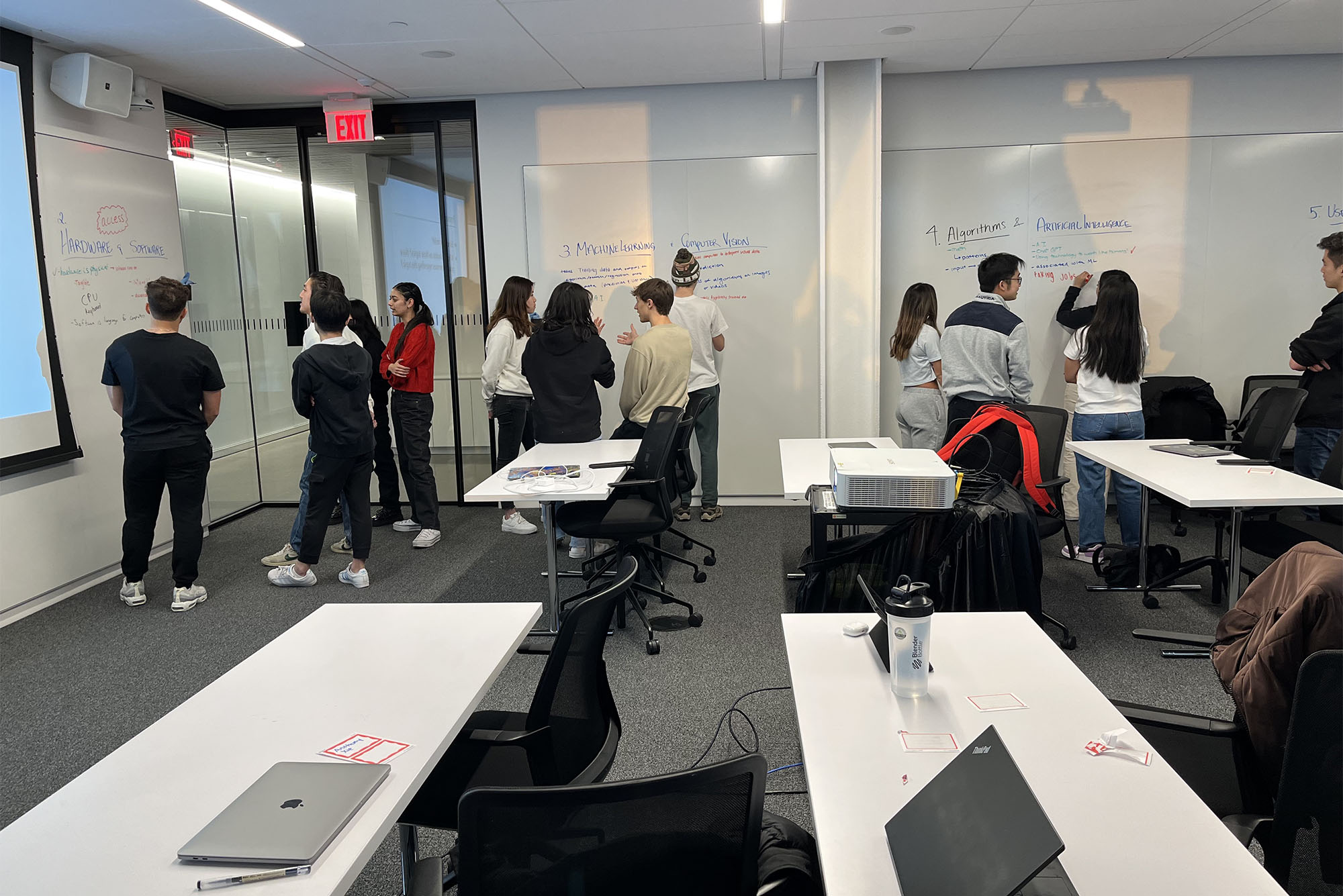 Photo: A group of college students in a modern classroom with shared tables and chairs with wheels on the bottom.