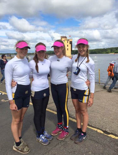 Photo: Four women wearing white long-sleeved shirts, black pants and shorts, and pink visor caps, smiles and pose together.