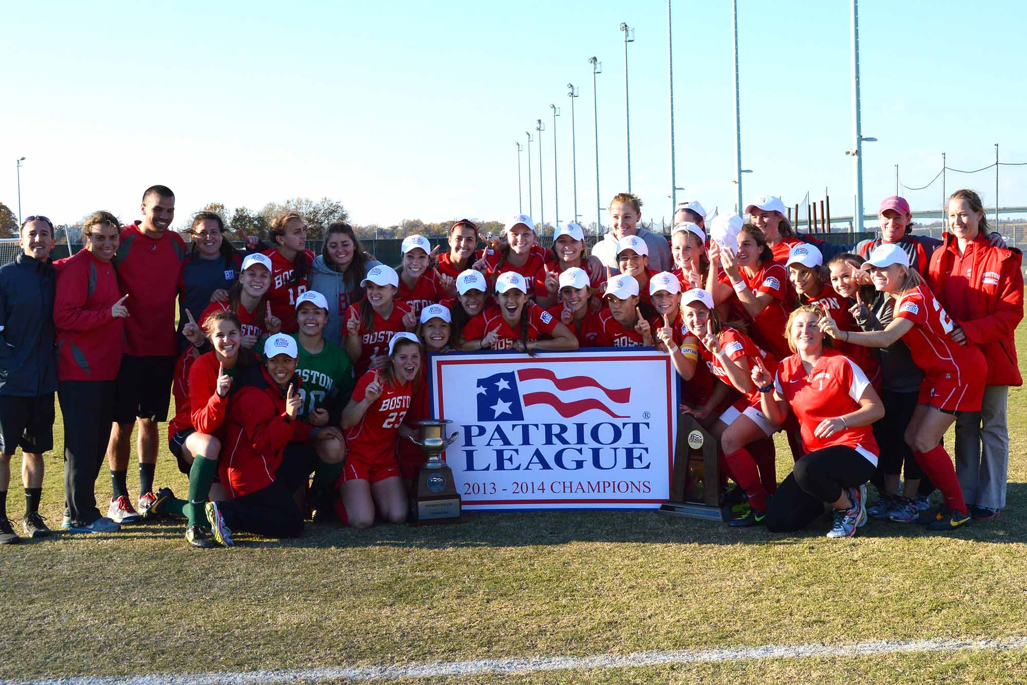 Photo: The BU Women's Soccer team sits on field with a banner reading "Patriot League Champions" after winning the Patriot League in 2013