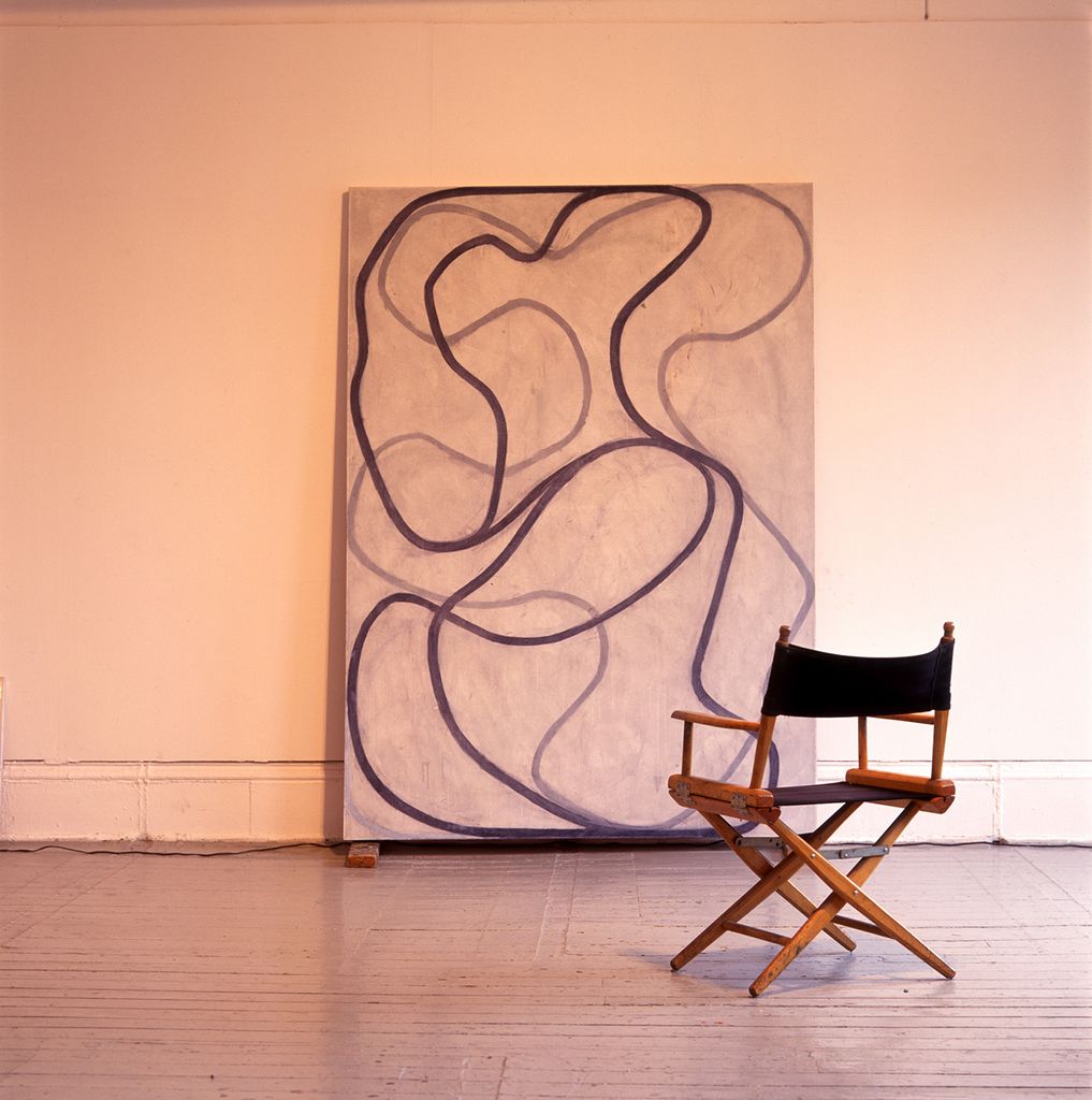 Photo: A large canvas featuring a painting of large black squiggles rests against a wall. A small black canvas chair sits in front of it.