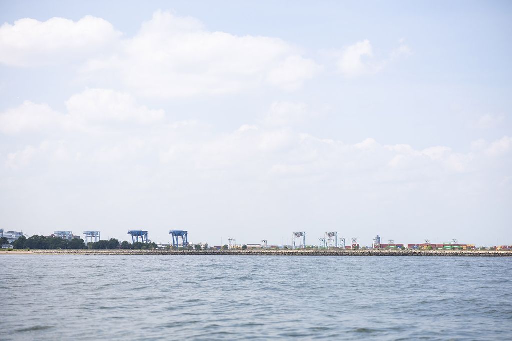 Photo: Wide shot of the Boston harbor. A large body of water is shown with a distant shoreline with houses on it.