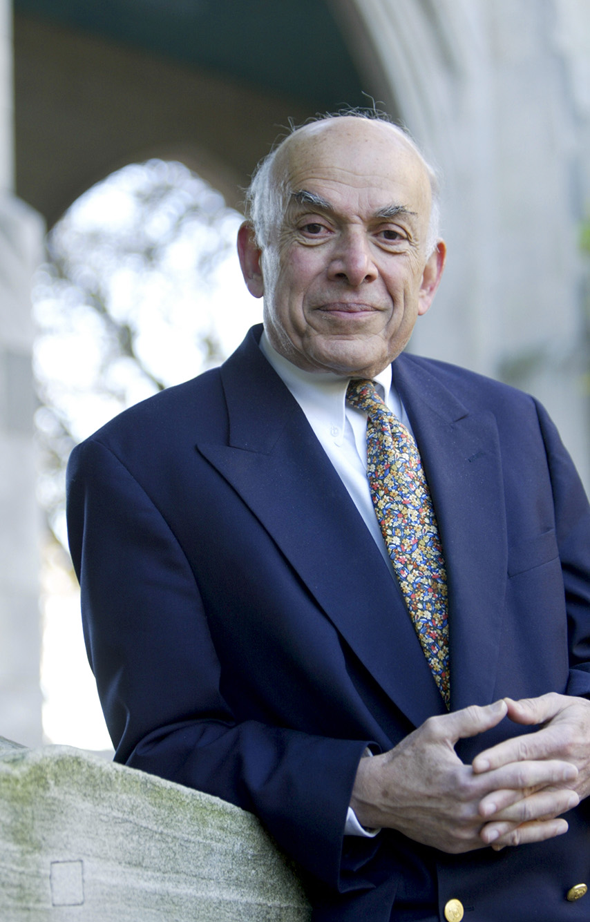 Photo: Portrait of Aram V. Chobanian standing outside Marsh Chapel on the B.U. campus. An older man balding man with white hair and wearing a white collared shirt, paisley tie, and navy suit, smiles and looks at the camera.