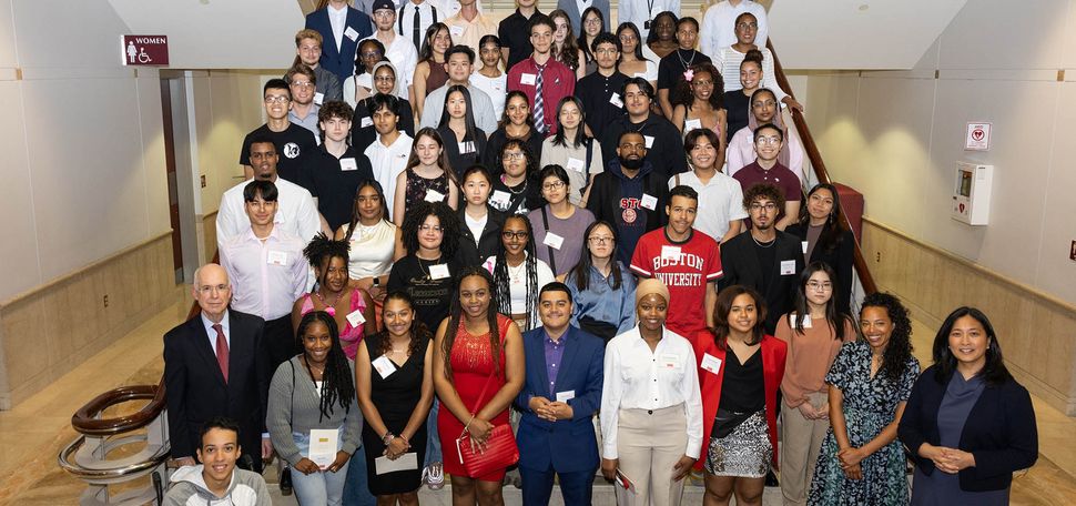 Photo: Large overhead shot of 2023's Menino Scholarship and ComCommunity Service Award recipients. Students in business casual attire pose on a large set of stairs together. Also pictured are interim President Ken Freeman.