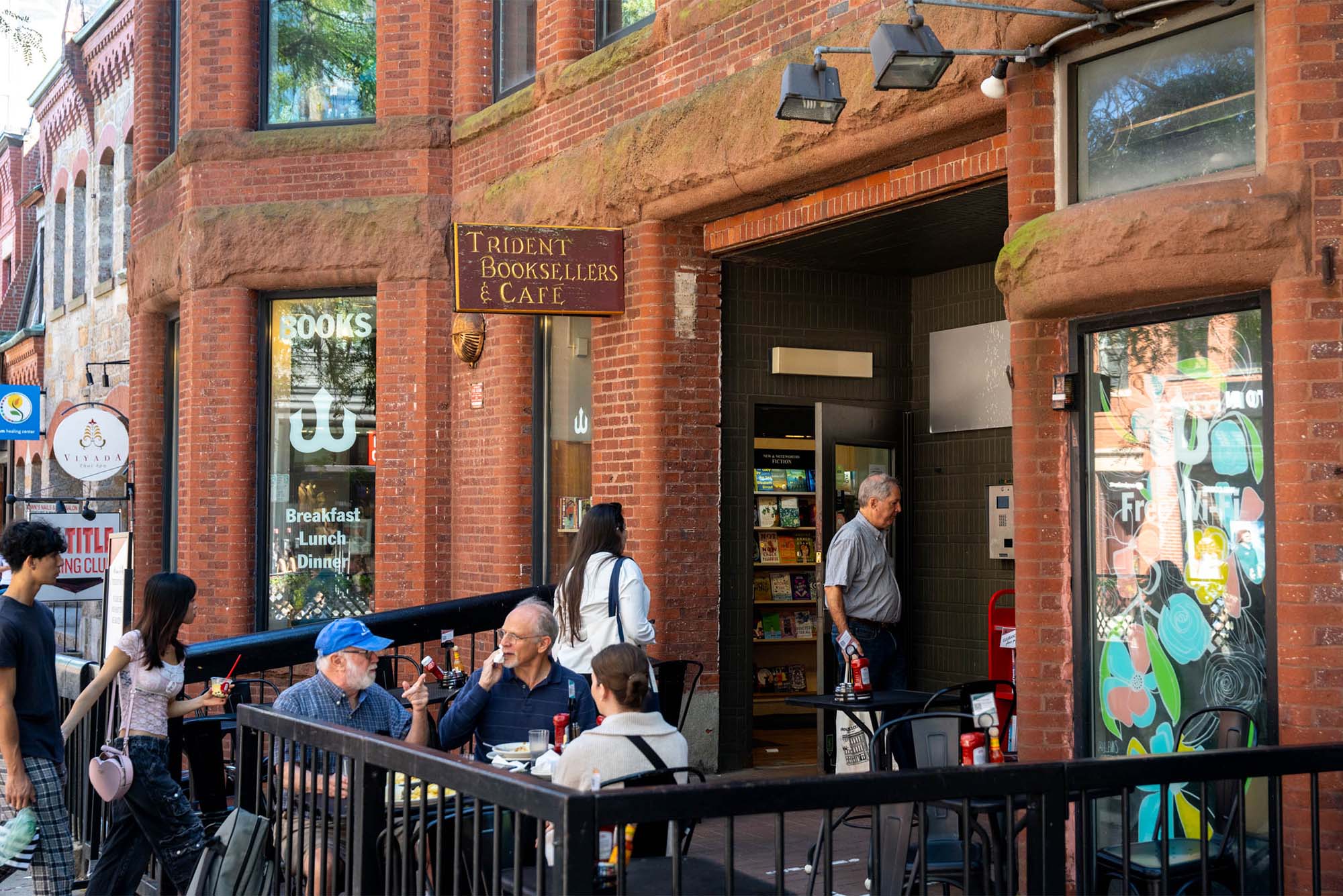 Photo: Trident Booksellers and Cafe, a brick building with iron fences in front in Boston, MA, on a busy day.