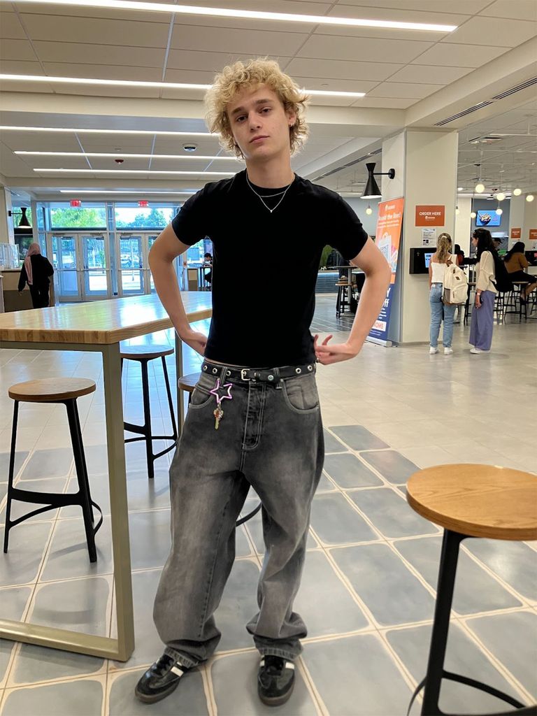 Photo: A student with puffy blonde hair poses in jeans and a black t shirt, with a unique star keychain hanging off a belt loop