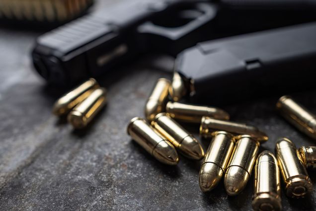 Photo: A handgun with bullets laying on a table