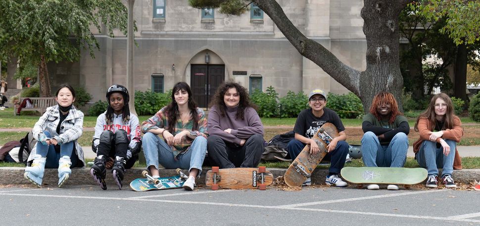 Photo: The BU Girls' Skateboarding Club poses for a photo along the BU Beach, an outdoor area where BU students can relax and unwind outside.