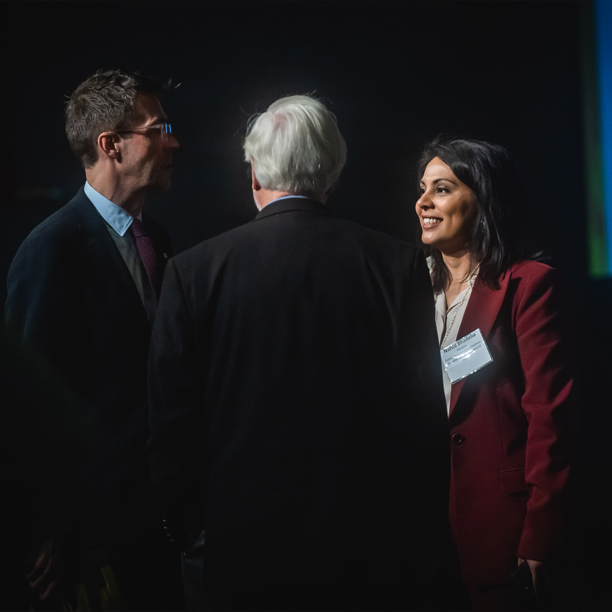 Photo: Dr. Nahid Bhadelia, founding director of BU Center for Emerging Infectious Diseases Policy and Research mingles during MassCPR Symposium Pandemic Preparedness at Boston University on November 14, 2023. A woman and two men in formal attire having a conversation.