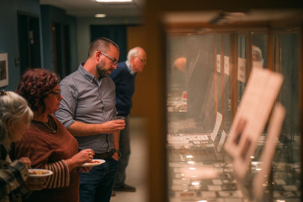 Photo: Visitors are shown taking a tour of A tour of the new Mary C. Beaudry Community Archaeology Center. They hold drinks and appetizers as they view the dispays.