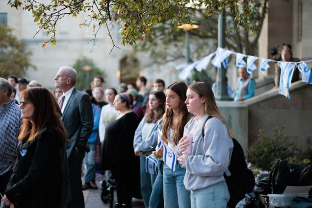 Photo: Students and BU faculty wear somber looks and hold up the Israel flag at a vigil.
