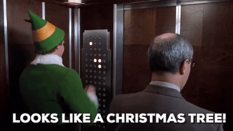 This is a gif from the movie Elf. Elf is in the elevator with a stranger and he is pressing every single button and says "It looks like a Christmas tree." There is text at the bottom of the screen that reflects what he is saying. It is in a white, bold font.