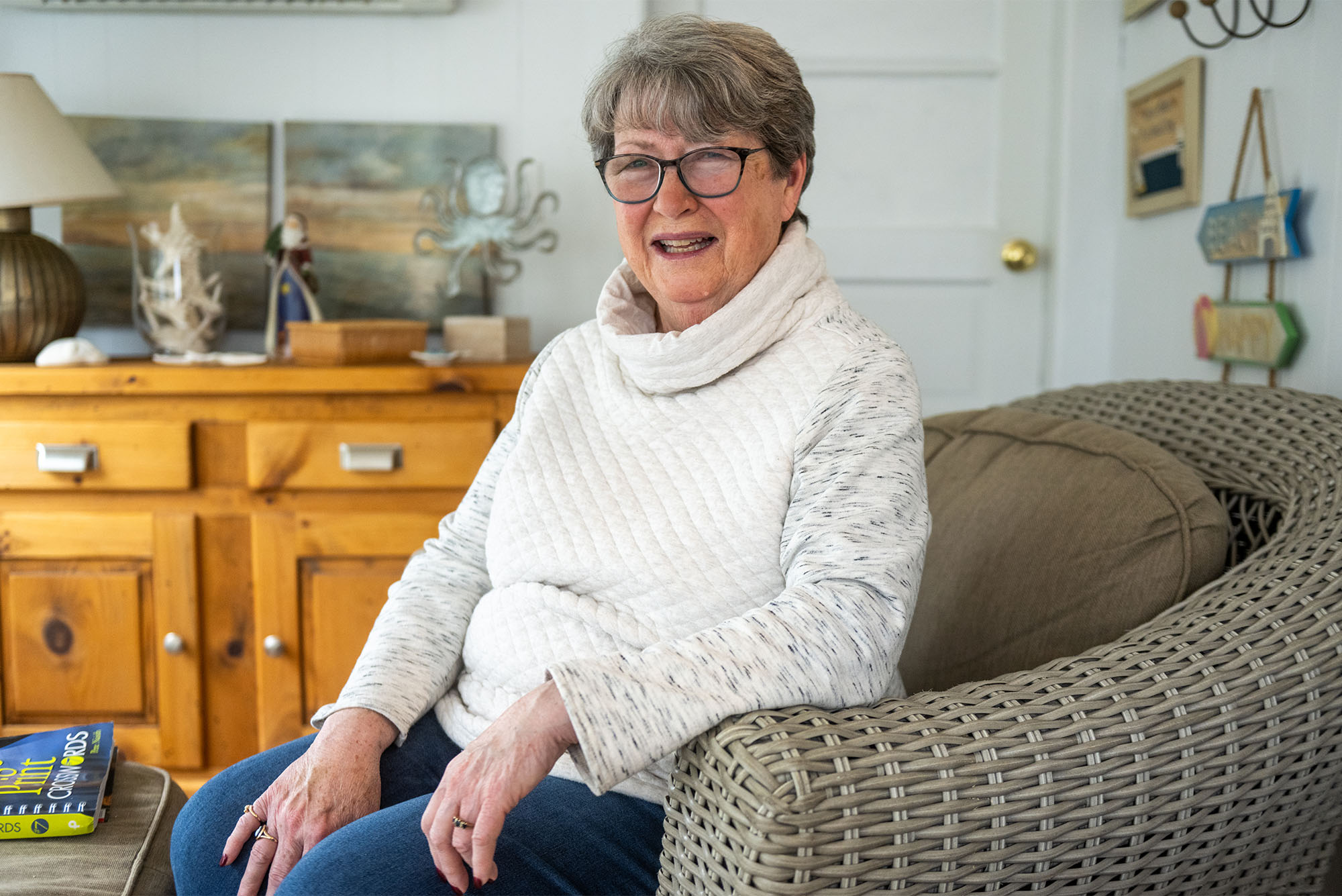 Photo: An older woman wearing a lovely sweater sitting in a chair in a comfortable living room setting