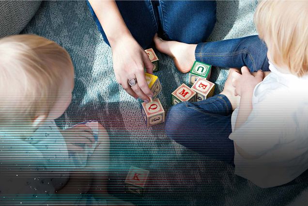 Photo: A family with two children playing with blocks with english letters on them