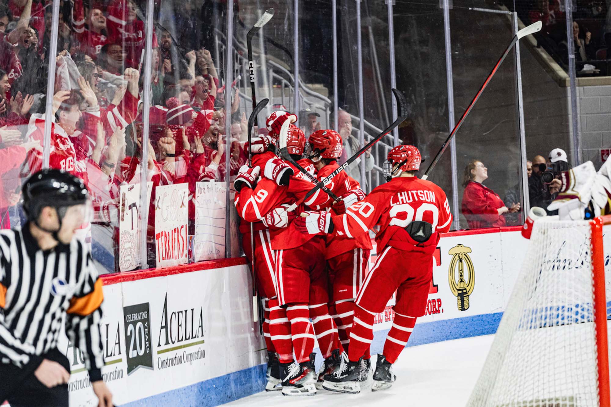 Photo: A large group of college hockey players celebrate near their bench in red jerseys as an onlooking crowd goes wild